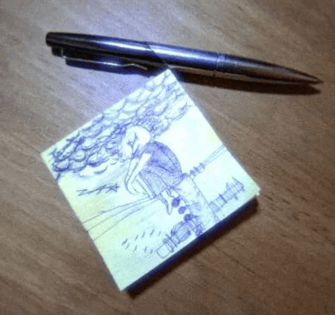 A tiny detailed sketch on a sticky note beside a pen